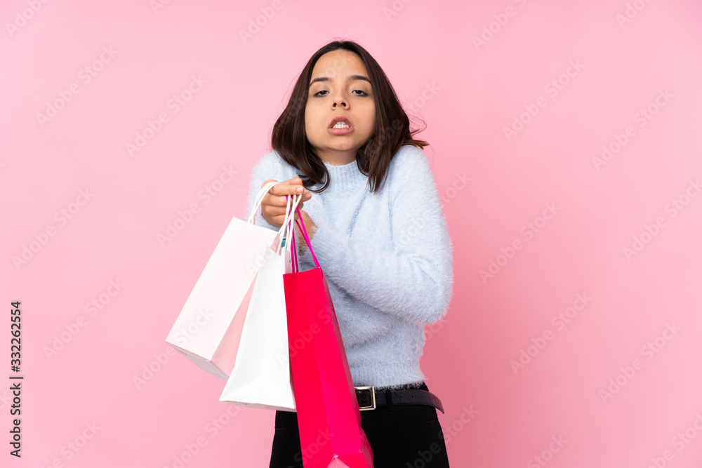 Young woman with shopping bag over isolated pink background freezing