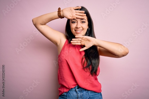 Young brunette woman wearing casual summer shirt over pink isolated background Smiling cheerful playing peek a boo with hands showing face. Surprised and exited