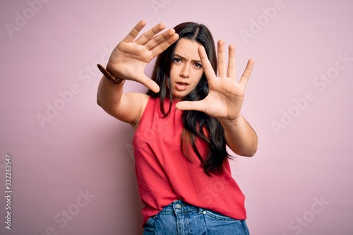 Young brunette woman wearing casual summer shirt over pink isolated background doing frame using hands palms and fingers, camera perspective