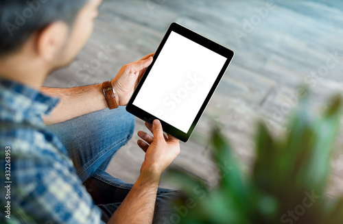 Mockup of a man holds tablet computer with isolated screen in his hands. View from above. Clipping path. photo