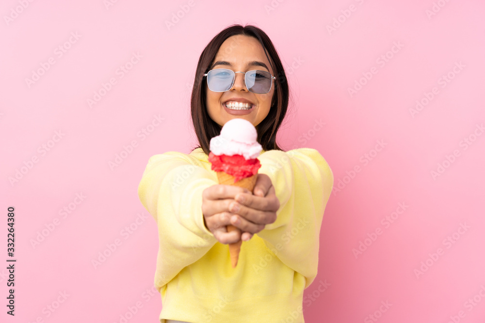 Young brunette girl holding a cornet ice cream over isolated pink background holding copyspace imaginary on the palm to insert an ad Young brunette girl holding a cornet ice cream over isolated pink background holding copyspace imaginary on the palm to insert an ad