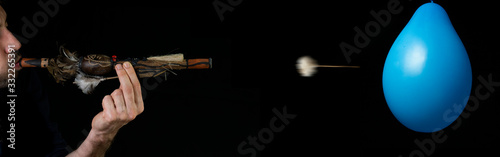 Blowpipe (blowgun) and darts from indegenous tribe of Amazon (near Manaus) isolated on black background shooting balloon photo