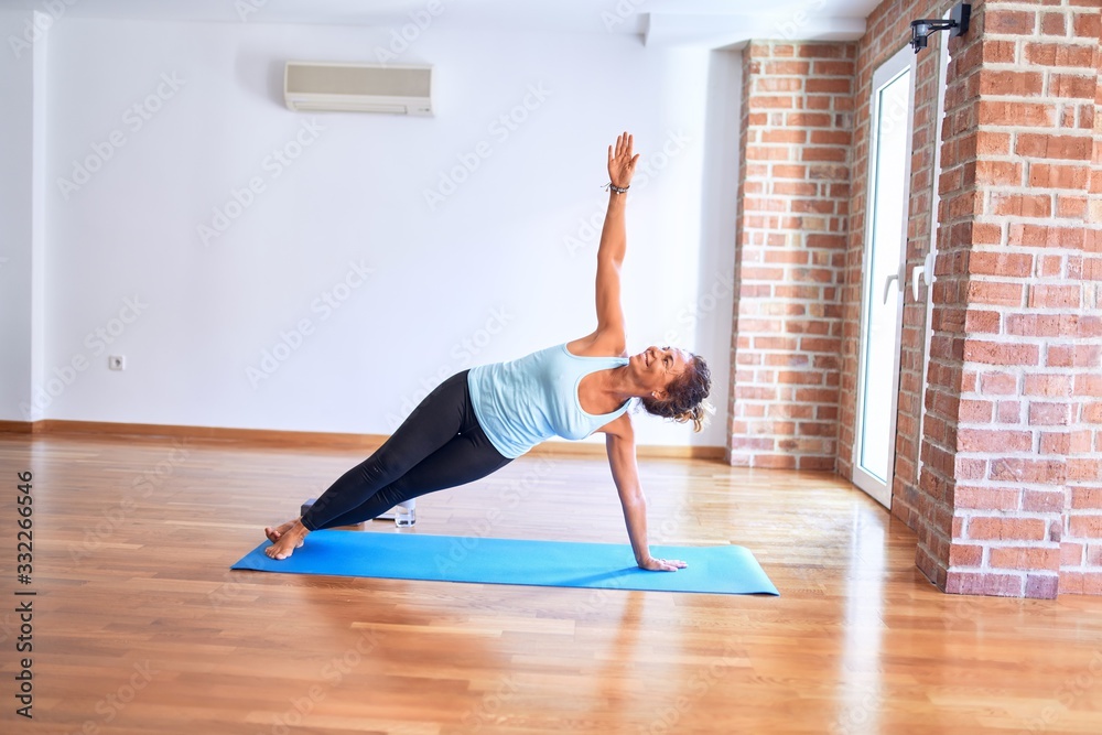 Obraz premium Middle age beautiful sportwoman smiling happy on mat. Practicing yoga doing side plank pose at gym