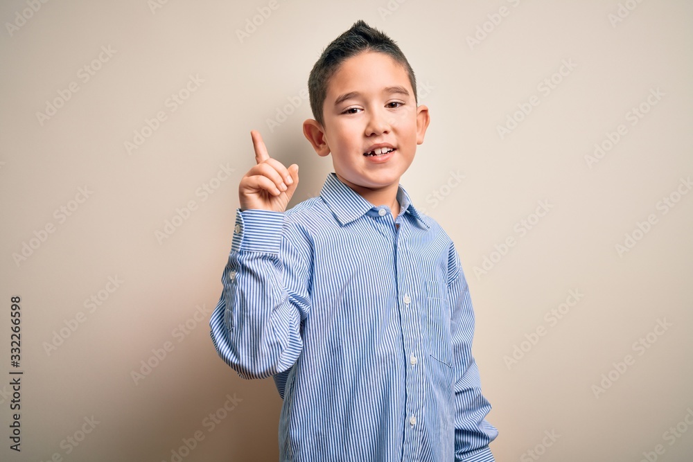 Young little boy kid wearing elegant shirt standing over isolated background showing and pointing up with finger number one while smiling confident and happy. Young little boy kid wearing elegant shirt standing over isolated background showing and pointing up with finger number one while smiling confident and happy.