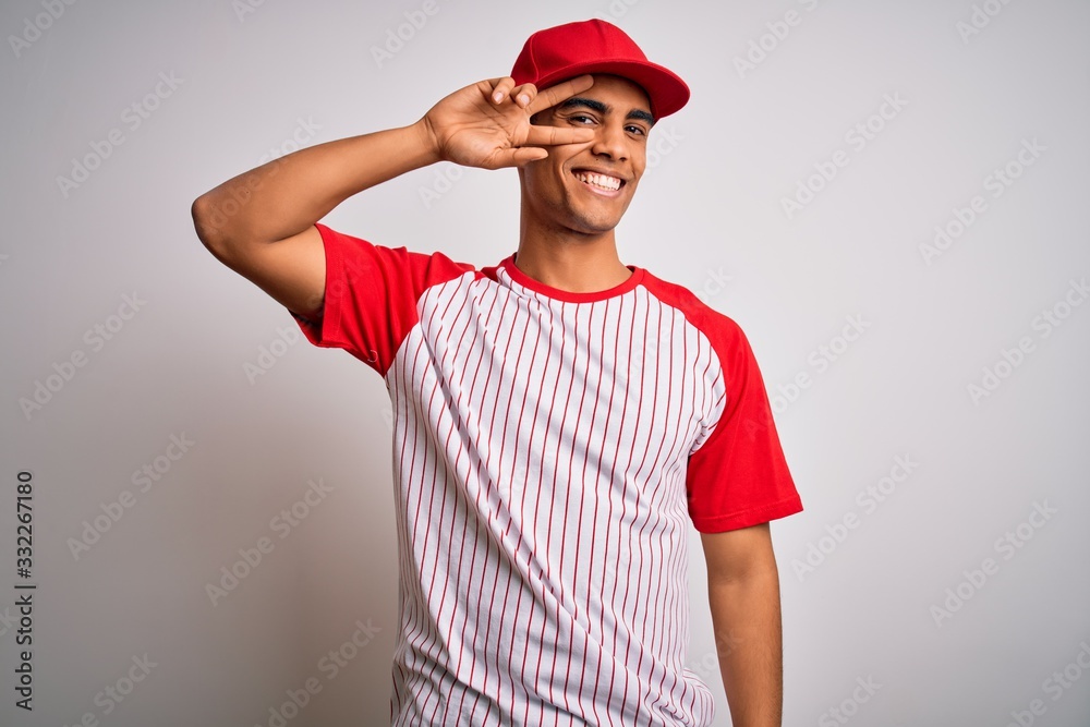 Young handsome african american sportsman wearing striped baseball t-shirt and cap Doing peace symbol with fingers over face, smiling cheerful showing victory