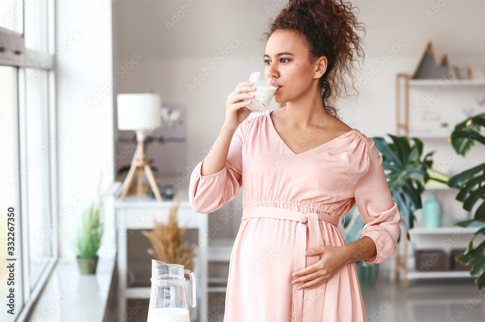 Young pregnant African-American woman drinking milk at home Young pregnant African-American woman drinking milk at home