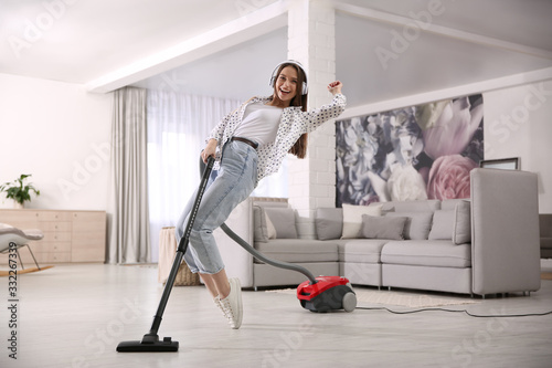 Young woman having fun while vacuuming at home