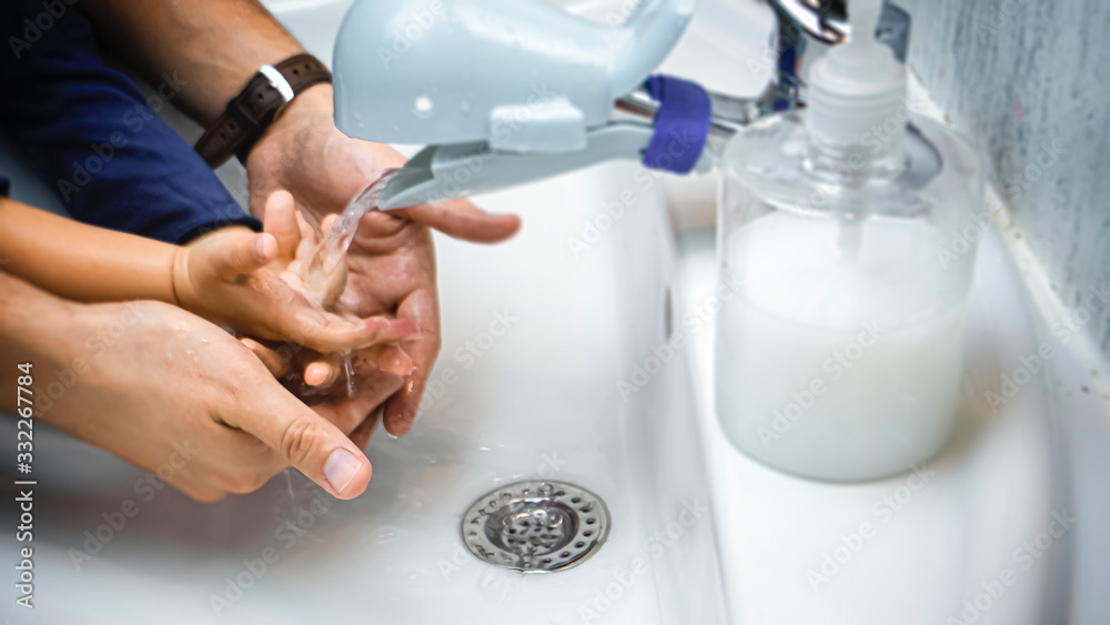 Father is washing hands of his baby toddler, rubbing with soap for corona virus prevention, hygiene to stop spreading coronavirus. Concept of teaching and learning healthy habits from an early age. 