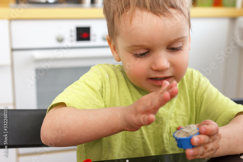 Cute little boy age of 3 years plays kinetic sand at home. Occupation with a child in quarantine.