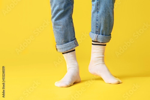 Male legs in socks and jeans on color background © Pixel-Shot