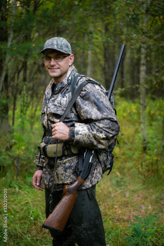 Fototapeta premium Silhouette of a hunter on the background of the morning red dawn. Stands at the ready with a gun.