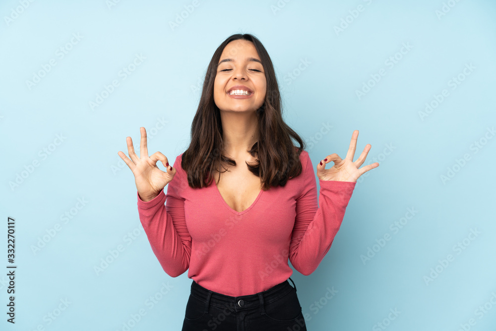 Young mixed race woman isolated on blue background in zen pose Young mixed race woman isolated on blue background in zen pose
