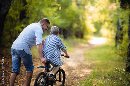 young father teaching his smiling son how to ride a bike © romankosolapov