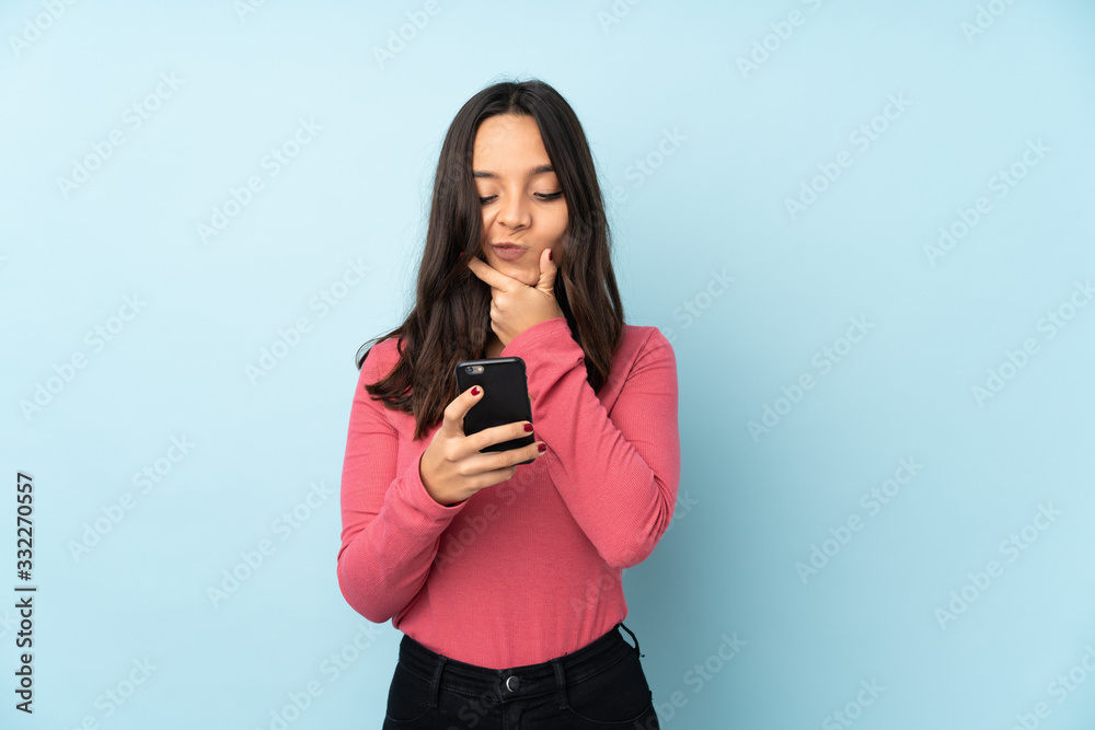 Young mixed race woman isolated on blue background thinking and sending a message Young mixed race woman isolated on blue background thinking and sending a message
