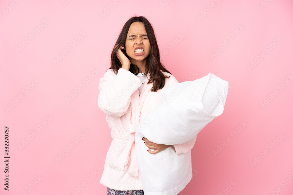 Young woman in pajamas isolated on pink background frustrated and covering ears Young woman in pajamas isolated on pink background frustrated and covering ears