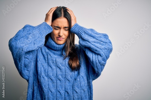 Young beautiful brunette woman wearing casual turtleneck sweater over white background suffering from headache desperate and stressed because pain and migraine. Hands on head.