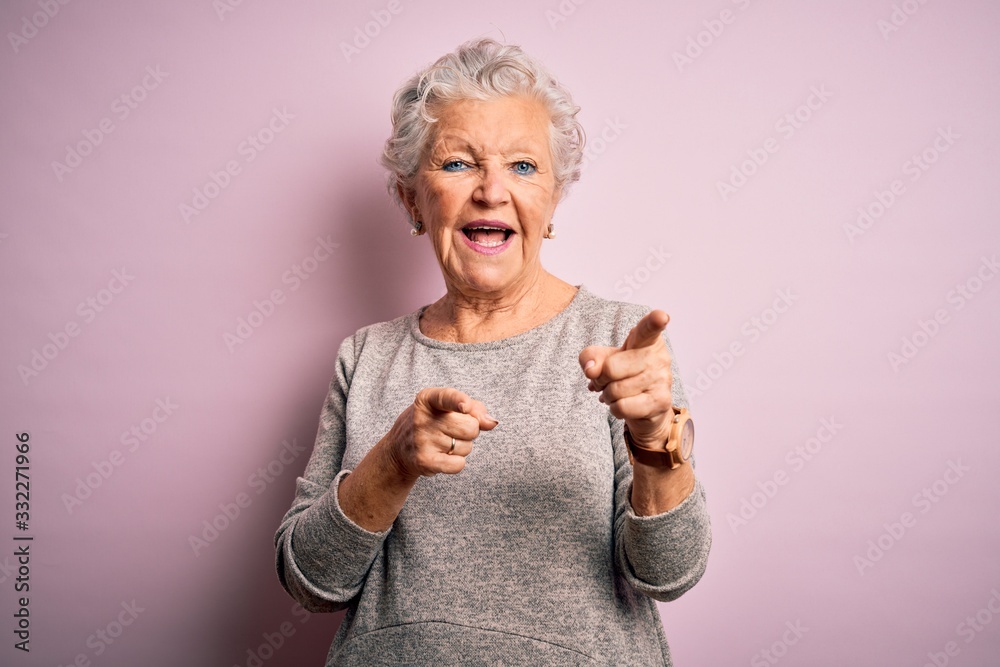 Senior beautiful woman wearing casual t-shirt standing over isolated pink background pointing fingers to camera with happy and funny face. Good energy and vibes. Senior beautiful woman wearing casual t-shirt standing over isolated pink background pointing fingers to camera with happy and funny face. Good energy and vibes.