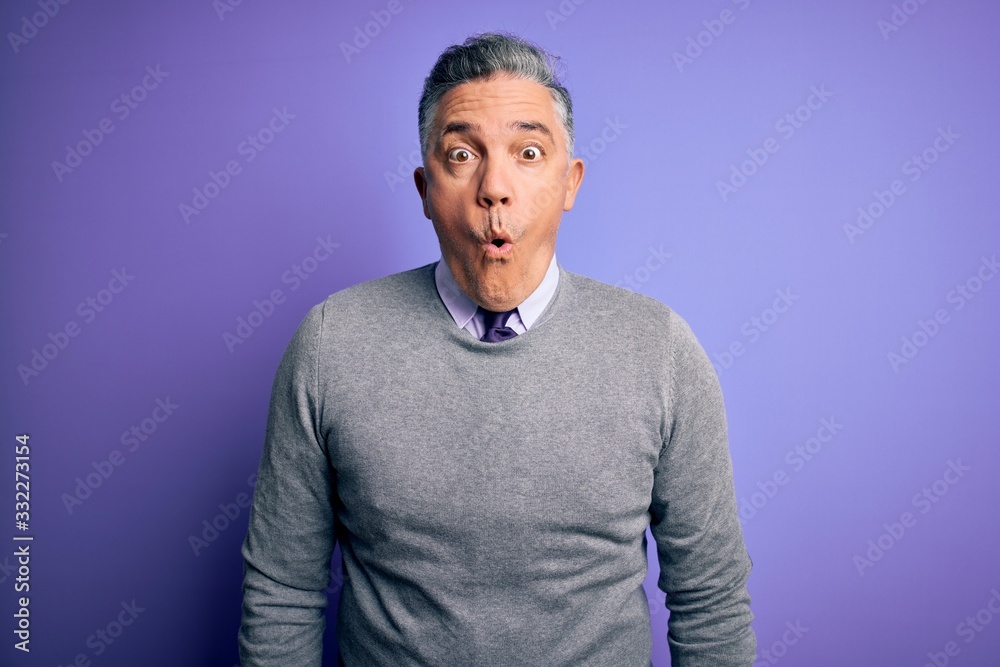 Middle age handsome grey-haired man wearing elegant sweater over purple background afraid and shocked with surprise expression, fear and excited face. Middle age handsome grey-haired man wearing elegant sweater over purple background afraid and shocked with surprise expression, fear and excited face.