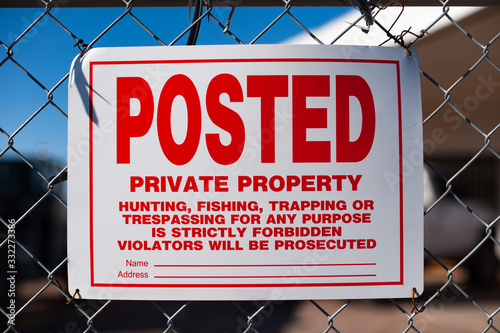 Posted private property sign warning trespassers on a chain link fence photo