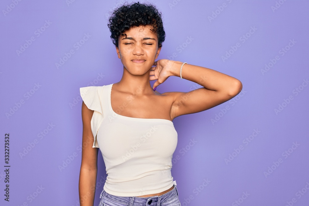 Young beautiful african american afro woman wearing casual t-shirt over purple background Suffering of neck ache injury, touching neck with hand, muscular pain Young beautiful african american afro woman wearing casual t-shirt over purple background Suffering of neck ache injury, touching neck with hand, muscular pain