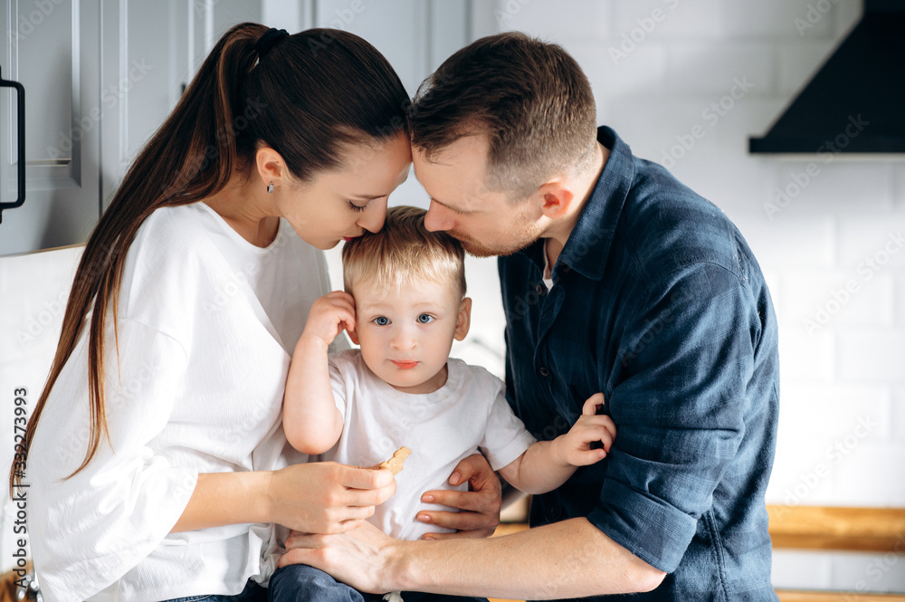 Sensual photo of a happy family. Parents kiss their cute baby boy at their cozy home Sensual photo of a happy family. Parents kiss their cute baby boy at their cozy home