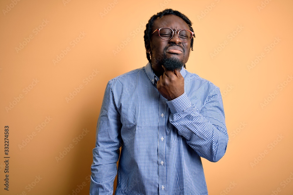 Young handsome african american man wearing shirt and glasses over yellow background Touching painful neck, sore throat for flu, clod and infection