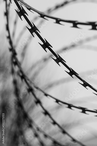 Monochrome photo of detail of barbed wire. Steel border. Prison, military or quarantine concept photo