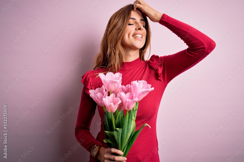 Young beautiful brunette woman holding bouquet of pink tulips over isolated background smiling confident touching hair with hand up gesture, posing attractive and fashionable Young beautiful brunette woman holding bouquet of pink tulips over isolated background smiling confident touching hair with hand up gesture, posing attractive and fashionable