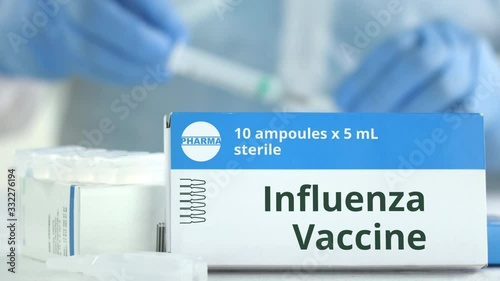 Box with influenza vaccine on the table against blurred lab assistant or doctor. Fictional phaceutical logo photo