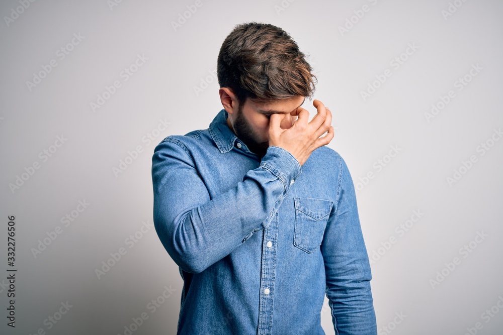 Young handsome blond man with beard and blue eyes wearing casual denim shirt tired rubbing nose and eyes feeling fatigue and headache. Stress and frustration concept. Young handsome blond man with beard and blue eyes wearing casual denim shirt tired rubbing nose and eyes feeling fatigue and headache. Stress and frustration concept.