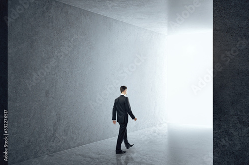 Businessman in interior with empty concrete wall