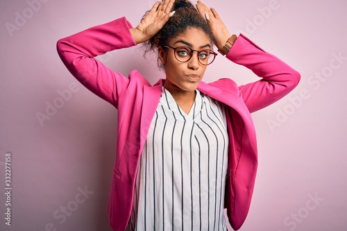 Beautiful african american businesswoman wearing jacket and glasses over pink background Doing bunny ears gesture with hands palms looking cynical and skeptical. Easter rabbit concept.