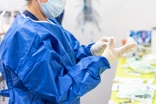 Surgeon putting on sterile gloves in an operating room .