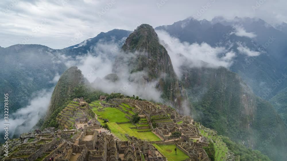 Zoom out time lapse view of mysterious Inca ruins of Machu Picchu shrouded in mist high in the Andes mountain range, Cusco Region, Peru.