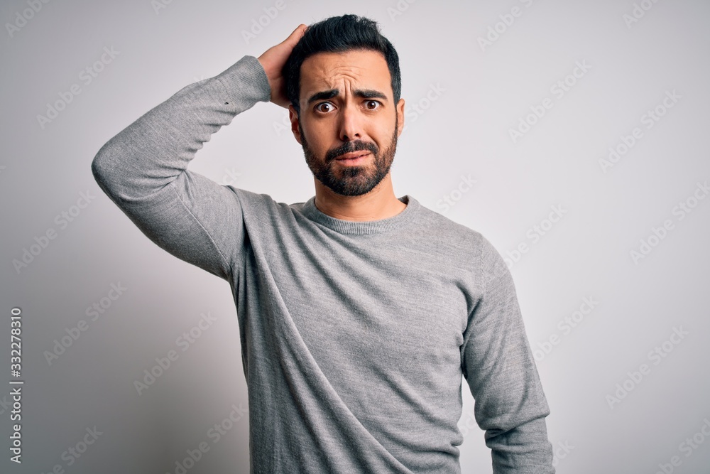 Young handsome man with beard wearing casual sweater standing over white background confuse and wonder about question. Uncertain with doubt, thinking with hand on head. Pensive concept. Young handsome man with beard wearing casual sweater standing over white background confuse and wonder about question. Uncertain with doubt, thinking with hand on head. Pensive concept.