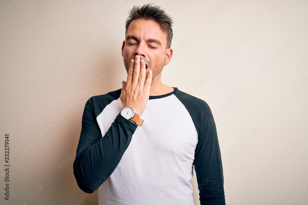 Young handsome man wearing casual t-shirt standing over isolated white background bored yawning tired covering mouth with hand. Restless and sleepiness. Young handsome man wearing casual t-shirt standing over isolated white background bored yawning tired covering mouth with hand. Restless and sleepiness.