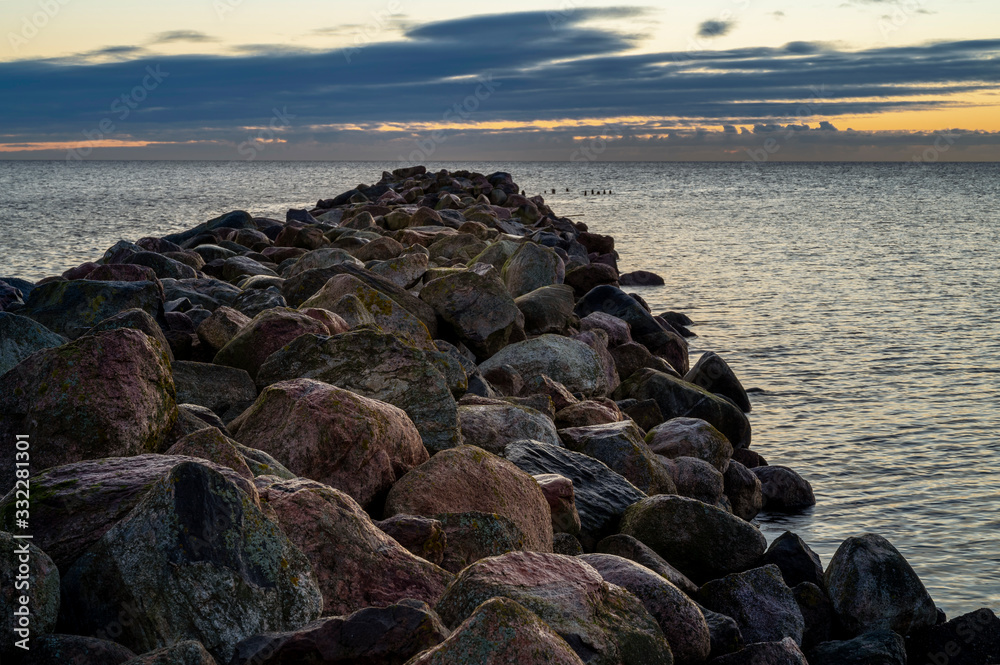Beautiful calm sunrise over the Baltic sea with old rocky pier in foreground Beautiful calm sunrise over the Baltic sea with old rocky pier in foreground