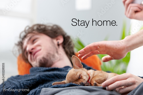 young man with puppy staying home to avoid virus infection photo