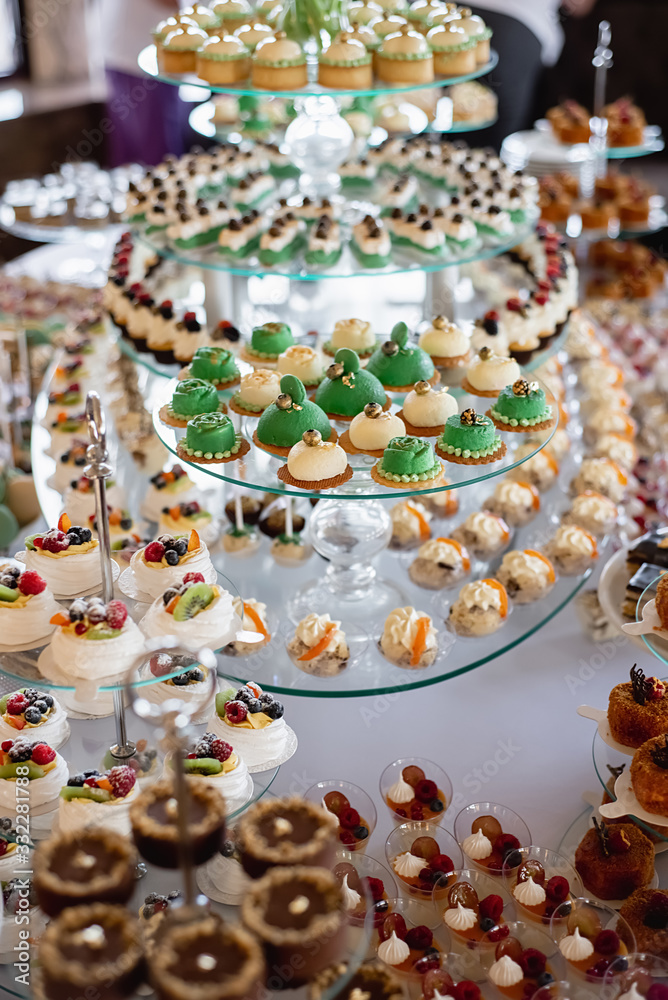 Close up of sweet table for wedding ceremony or birthday . Candy bar with a lot of different candies and sweet cakes. Selective focus. Party and holiday celebration concept