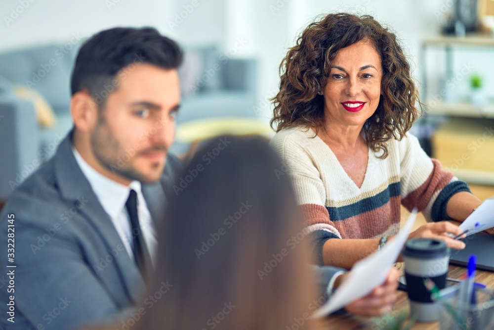Group of business workers working together. Sitting on desk using laptop reading documents at the office