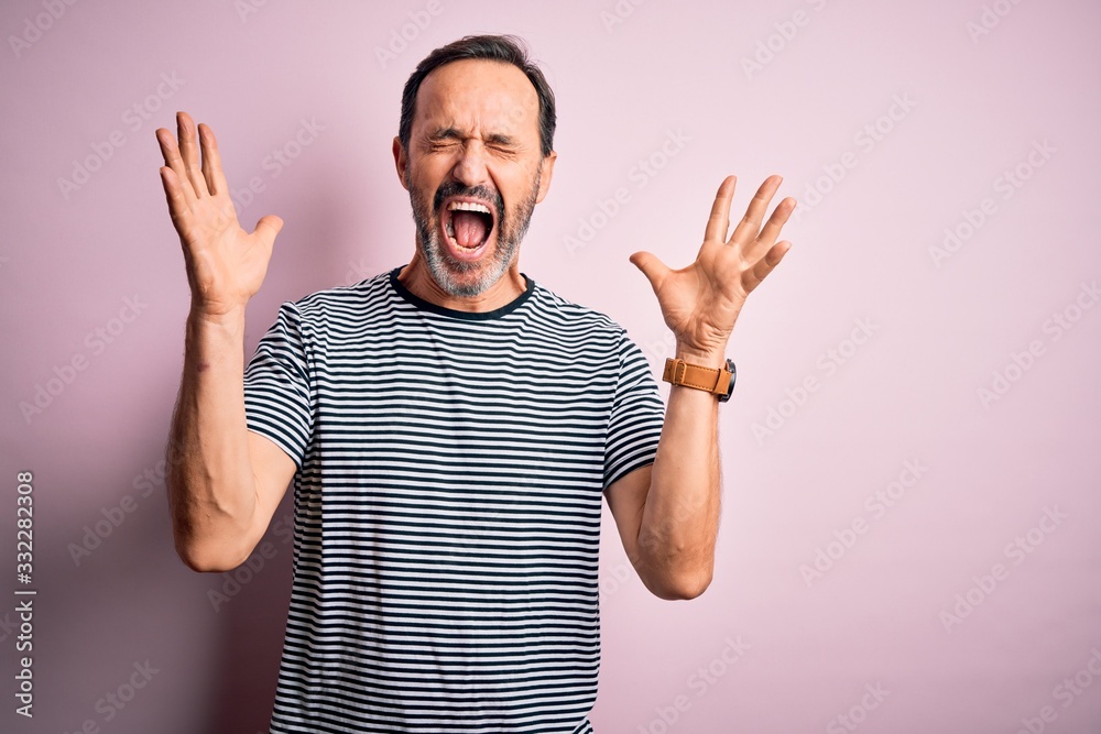 Middle age hoary man wearing casual striped t-shirt standing over isolated pink background celebrating mad and crazy for success with arms raised and closed eyes screaming excited. Winner concept Middle age hoary man wearing casual striped t-shirt standing over isolated pink background celebrating mad and crazy for success with arms raised and closed eyes screaming excited. Winner concept