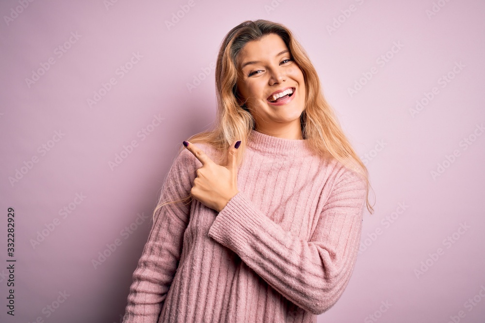 Young beautiful blonde woman wearing casual pink sweater over isolated background cheerful with a smile of face pointing with hand and finger up to the side with happy and natural expression on face Young beautiful blonde woman wearing casual pink sweater over isolated background cheerful with a smile of face pointing with hand and finger up to the side with happy and natural expression on face