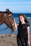 Dziewczynka z koniem na plaży zamyślona
