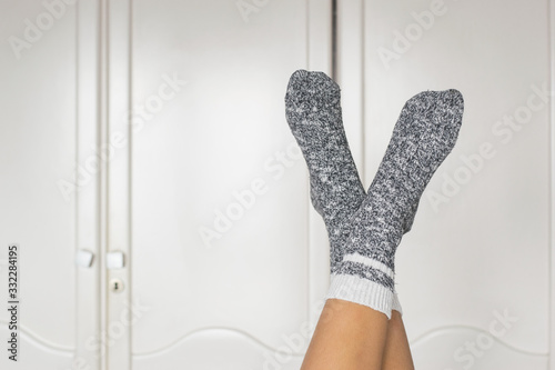 close-up of a woman in pajamas and socks with her feet against the wall in concept of staying at home
