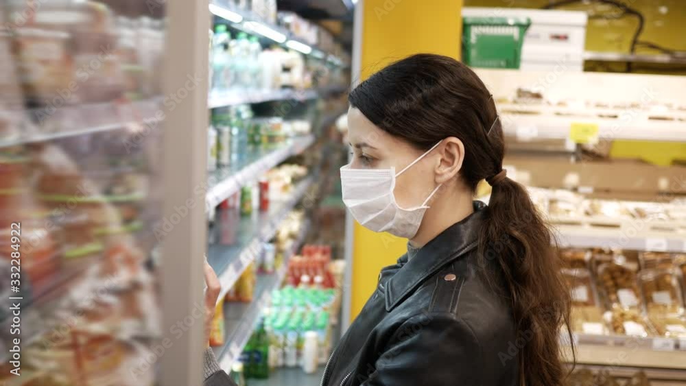 beautiful brunette young woman in medical masks at supermarket. pandemic. Selects products beautiful brunette young woman in medical masks at supermarket. pandemic. Selects products