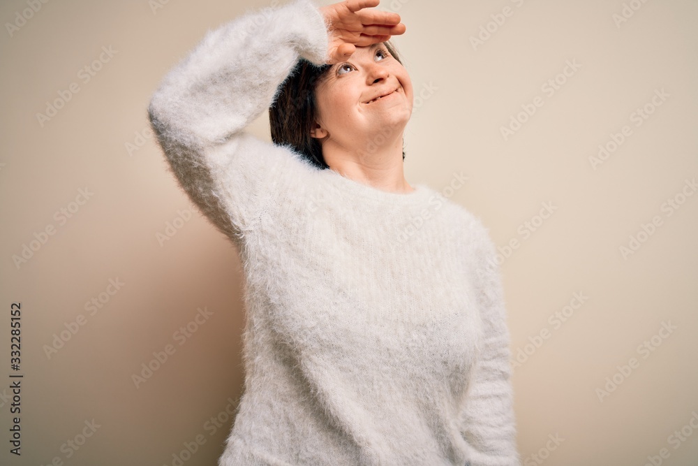 Obraz premium Young down syndrome woman standing over isolated background very happy and smiling looking far away with hand over head. Searching concept.
