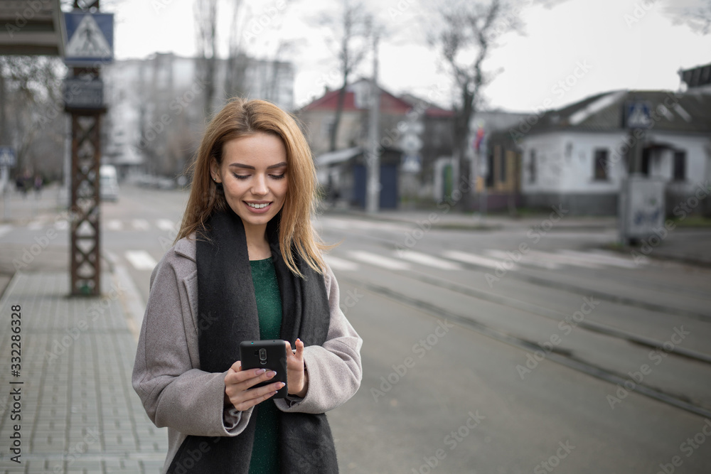 Girl writes message at smartphone on tram stop. Girl writes message at smartphone on tram stop.