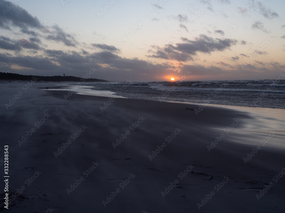 Sunset over Baltic Sea, empty beach, waves on the sea. Shot during windy weather. Leba, Poland.
