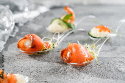 Delicious appetizers with red salmon fish and cheese mousse in glass spoon on grey banquet table. Gourmet food close up, snack, antipasti, close up