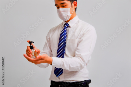 Businessman wears medical masks holding alcohol gel on gray background, corona virus concept, covid19 concept, medical concept photo